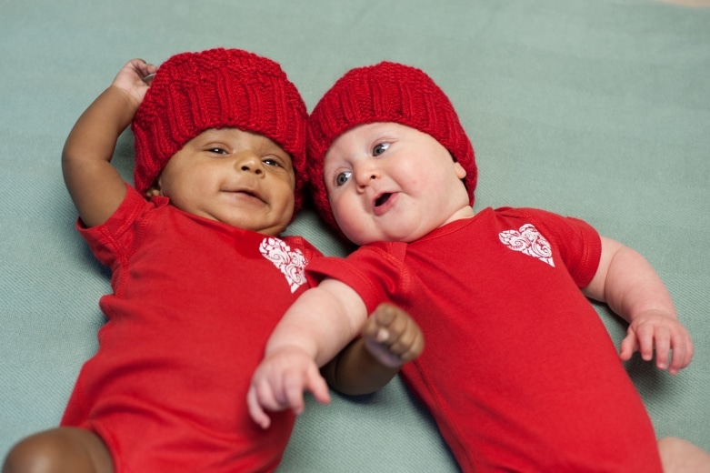 Two babies wearing red onesies and red hats