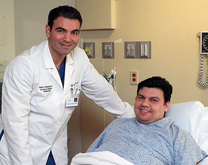 A doctor posing with a patient that is laying in hospital bed