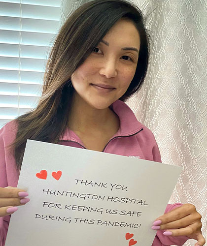 A woman holding a sign that reads Thank you Huntington Hospital for Keeping Us Safe during this pandemic!