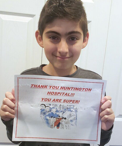 A boy holding a sign that reads Thank you Huntington Hospital!!! You are super!