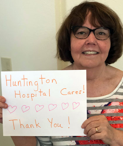 An older woman holds a sign reading Huntington Hospital Cares. Thank You!