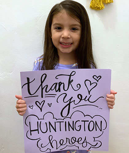 A little girl holds up a sign that reads Thank You Huntington Hospital