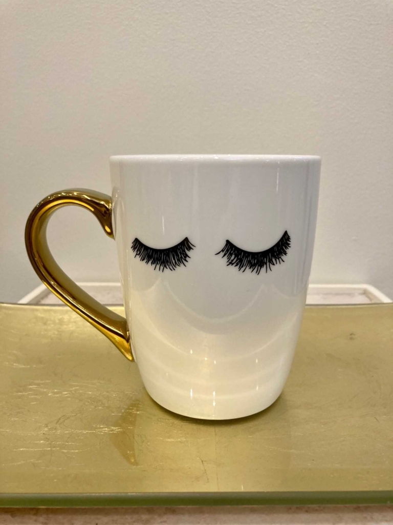 Coffee much with gold colored handle and eyelash design