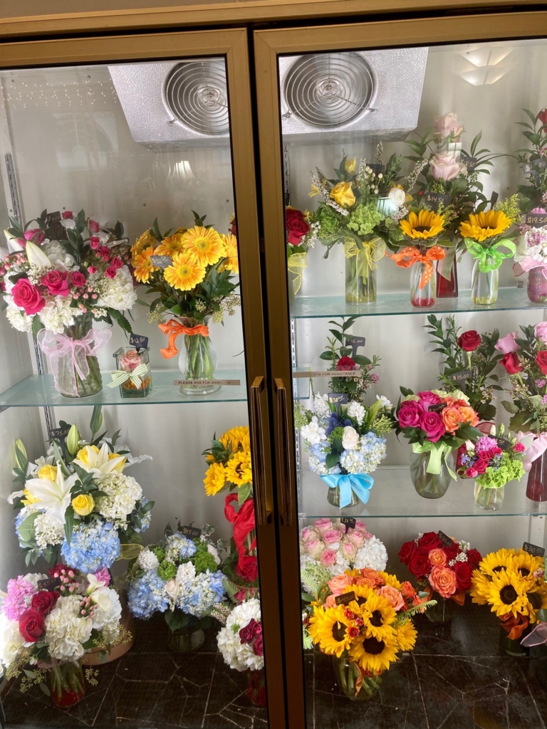 A refrigerated case with bundles of flowers