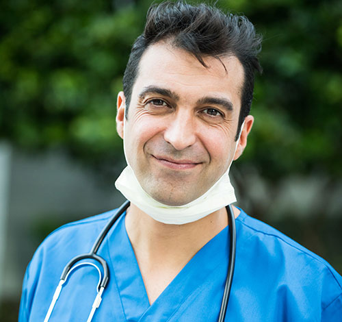 Attractive male armenian doctor smiling with mask around his chin