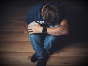 Person sitting alone on floor with head down in distress