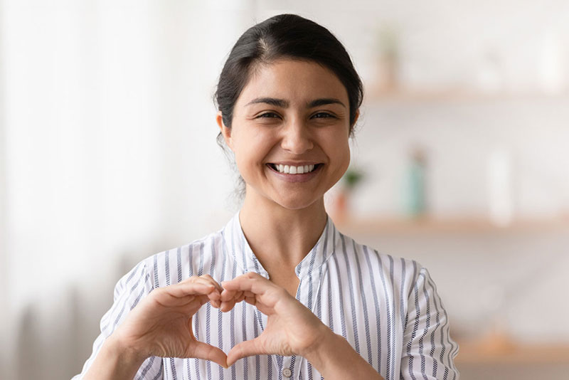 Smiling girl, holding her hands up in the shape of a heart