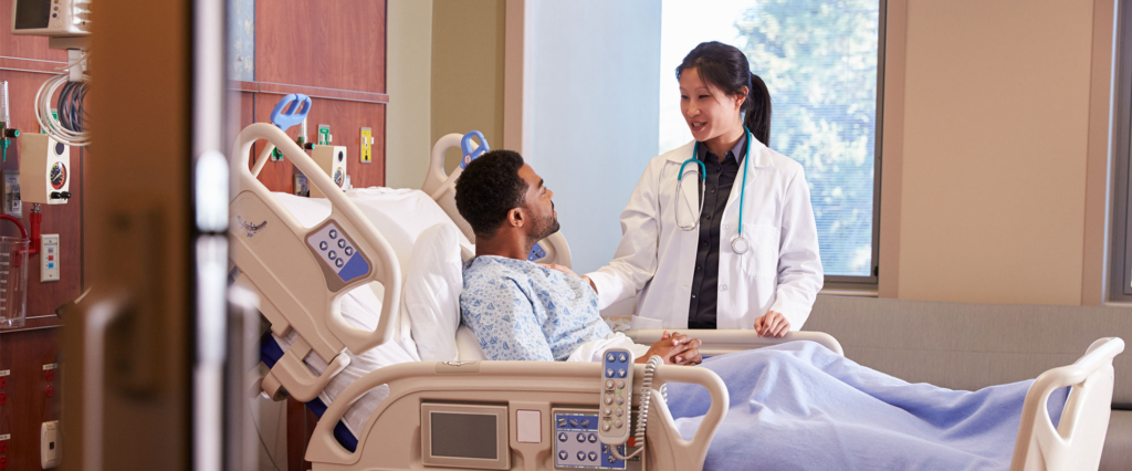 Doctor consults surgery patient in hospital bed