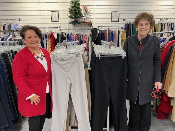 Two volunteers within racks of pants in the unique resale shop.