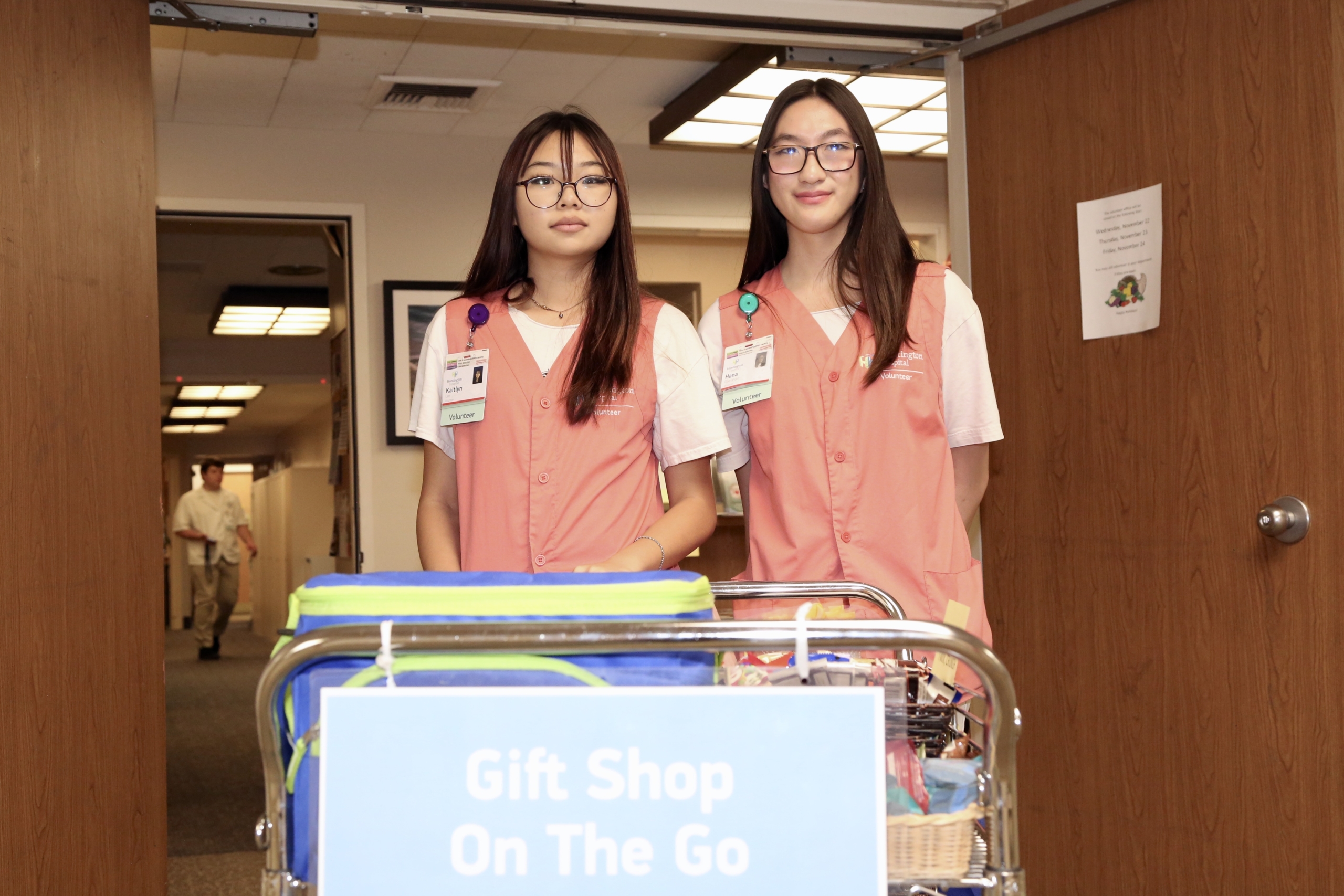 Two volunteers moving a mobile gift shop cart.