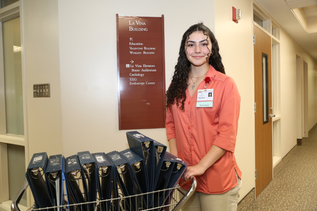 A volunteer moving a cart full of binders.