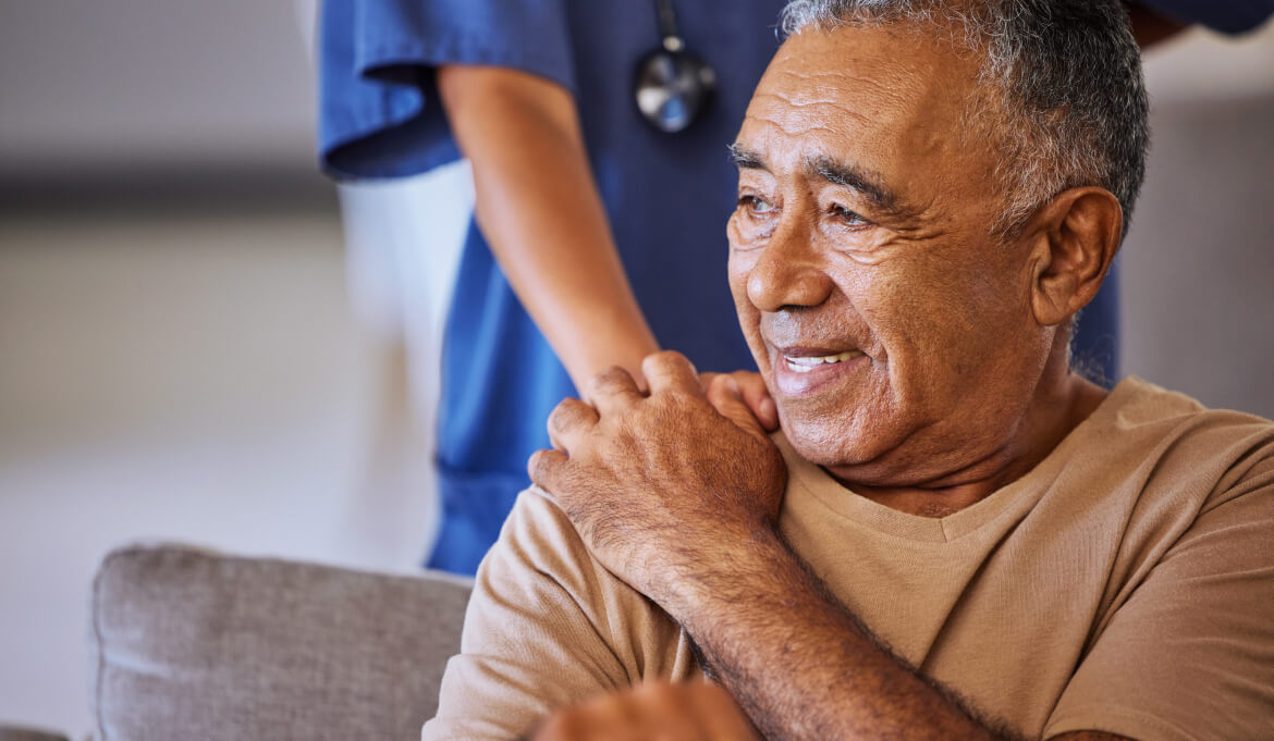 nurse putting hand on patient shoulder, who is smiling