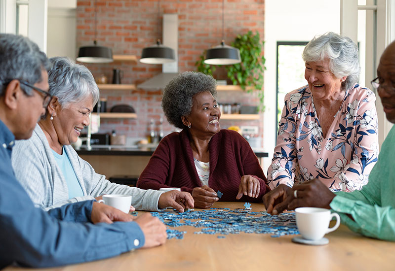 A group of seniors around a table with a jigsaw puzzle