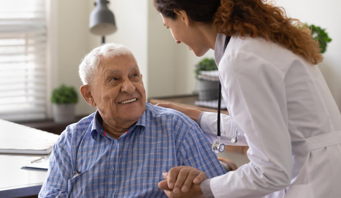 female doctor holding the hand of an older gentleman