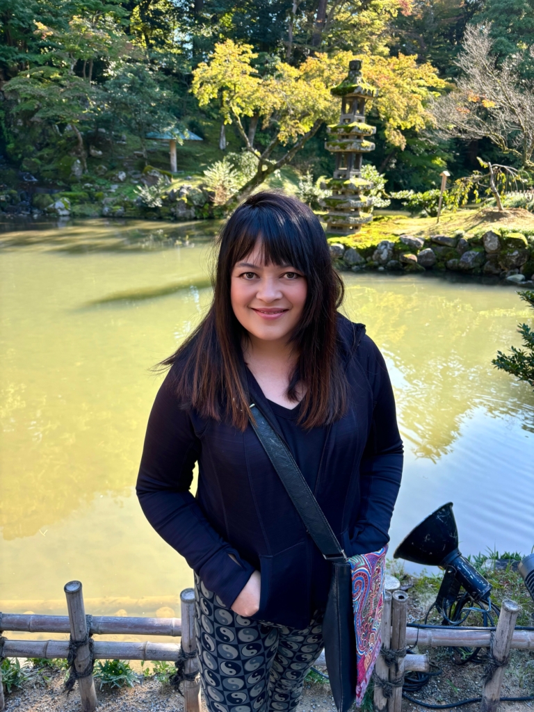 Woman smiling in front of Japanese garden pond