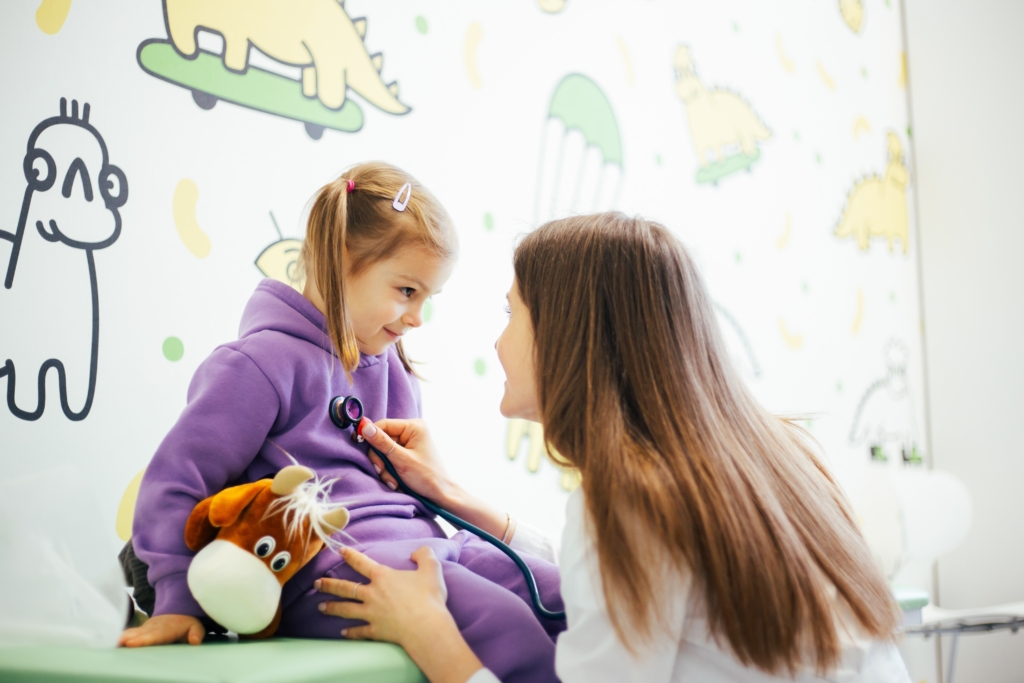 Healthcare worker giving a toy to a child in a hospital bed.